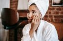 Seorang wanita muda dengan kulit sehat sedang mengaplikasikan serum anti-aging pada wajahnya, menunjukkan salah satu langkah penting dalam rutinitas perawatan kulit untuk menjaga keremajaan dan vitalitasnya. Produk anti-aging kini menjadi bagian tak terpisahkan dari gaya hidup modern untuk mengatasi tanda-tanda penuaan dini.