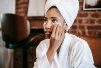 Seorang wanita muda dengan kulit sehat sedang mengaplikasikan serum anti-aging pada wajahnya, menunjukkan salah satu langkah penting dalam rutinitas perawatan kulit untuk menjaga keremajaan dan vitalitasnya. Produk anti-aging kini menjadi bagian tak terpisahkan dari gaya hidup modern untuk mengatasi tanda-tanda penuaan dini.