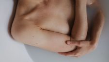 Ilustrasi seorang wanita sedang membersihkan area kewanitaan dengan air mengalir, menekankan pentingnya praktik kebersihan pribadi yang tepat untuk mencegah infeksi dan menjaga kesehatan organ intim secara optimal.