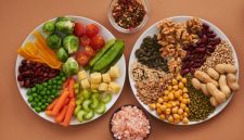 Piring yang berisi berbagai makanan bergizi seimbang, mencakup sayuran hijau segar, biji-bijian utuh, sumber protein seperti ikan, dan buah-buahan berwarna cerah, menunjukkan representasi visual dari pola makan sehat yang dianjurkan. Ilustrasi ini menekankan pentingnya variasi nutrisi dalam setiap sajian untuk mendukung kesehatan tubuh secara menyeluruh dan energi sepanjang hari.