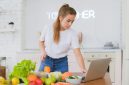 Seorang remaja perempuan sedang tersenyum sambil memegang semangkuk salad buah segar yang penuh warna, menunjukkan pilihan camilan sehat yang mendukung gaya hidup aktif dan penuh semangat. Gambar ini merepresentasikan pentingnya nutrisi seimbang bagi pertumbuhan remaja yang optimal.