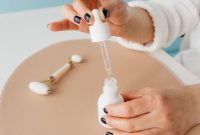 Seorang wanita sedang mengaplikasikan serum anti-aging di wajahnya, menunjukkan komitmen pada rutinitas perawatan kulit untuk menjaga keremajaan dan kesehatan kulit. Ilustrasi ini menggambarkan pentingnya perawatan teratur sebagai bagian dari upaya mendapatkan kulit awet muda.