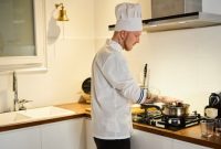 Seorang koki profesional bekerja di dapur yang tertata rapi, menggambarkan efisiensi dan perencanaan matang dalam mengelola waktu dan tugas. Konsep ini serupa dengan manajemen waktu produktif yang mengutamakan pengaturan prioritas dan alokasi blok waktu.