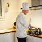 Seorang koki profesional bekerja di dapur yang tertata rapi, menggambarkan efisiensi dan perencanaan matang dalam mengelola waktu dan tugas. Konsep ini serupa dengan manajemen waktu produktif yang mengutamakan pengaturan prioritas dan alokasi blok waktu.