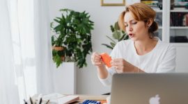 Seorang wanita tengah serius memeriksa laporan keuangan di laptopnya, menunjukkan dedikasi dalam mengelola anggaran dan merencanakan masa depan finansialnya secara mandiri dan bertanggung jawab.