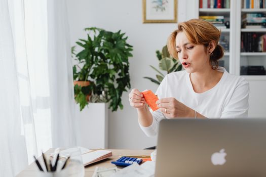 Seorang wanita tengah serius memeriksa laporan keuangan di laptopnya, menunjukkan dedikasi dalam mengelola anggaran dan merencanakan masa depan finansialnya secara mandiri dan bertanggung jawab.