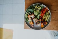 Sebuah piring berisi makanan seimbang yang kaya warna dan nutrisi, menampilkan sayuran segar, protein tanpa lemak, dan karbohidrat kompleks. Piring ini melambangkan pentingnya variasi dalam asupan makanan untuk menjaga kesehatan tubuh optimal setiap hari.