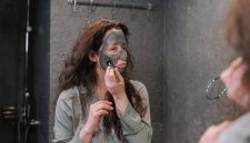 Seorang wanita sedang mengaplikasikan masker wajah buatan sendiri menggunakan bahan-bahan alami di dapur, menunjukkan kemudahan dan kepraktisan perawatan kecantikan dari rumah. Ia terlihat menikmati proses merawat kulit dengan sentuhan natural yang menyegarkan.
