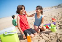 Seorang wanita tersenyum cerah saat mengaplikasikan tabir surya di pantai, menunjukkan pentingnya perlindungan kulit dari sinar matahari saat beraktivitas di luar ruangan. Tindakan sederhana ini merupakan investasi berharga demi kesehatan kulit jangka panjang.