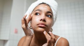 Seorang remaja perempuan dengan senyum cerah sedang mengaplikasikan pembersih wajah lembut, menunjukkan rutinitas perawatan kulit dasar yang aman untuk menjaga kesehatan kulit di usia muda. Pemilihan produk yang tepat merupakan kunci utama dalam merawat kulit remaja yang masih rentan terhadap perubahan hormon.