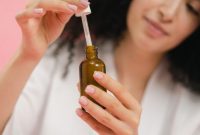 Seorang wanita mengaplikasikan serum wajah, menunjukkan salah satu langkah penting dalam rutinitas perawatan untuk mengatasi jerawat dan menjaga kesehatan kulit. Penggunaan serum yang tepat dapat membantu mengurangi peradangan serta produksi minyak berlebih pada wajah.