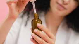 Seorang wanita mengaplikasikan serum wajah, menunjukkan salah satu langkah penting dalam rutinitas perawatan untuk mengatasi jerawat dan menjaga kesehatan kulit. Penggunaan serum yang tepat dapat membantu mengurangi peradangan serta produksi minyak berlebih pada wajah.