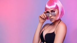 Seorang wanita menunjukkan gaya rambut bob asimetris yang dipadukan dengan pewarnaan rambut biru elektrik, merefleksikan tren eksplorasi gaya dan warna rambut yang diprediksi akan populer pada tahun 2026.