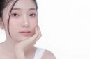 Seorang perempuan dengan kulit bercahaya alami di bawah sinar matahari pagi, menunjukkan hasil perawatan kulit yang konsisten dan gaya hidup sehat. Wajahnya memancarkan keindahan murni tanpa riasan berlebihan, memperlihatkan tekstur kulit yang halus dan merata.