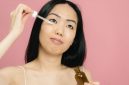 Seorang wanita mengaplikasikan serum anti-aging pada wajahnya, menunjukkan komitmen terhadap perawatan kulit demi mendapatkan tampilan yang sehat dan awet muda. Menggunakan produk yang tepat adalah kunci untuk menjaga elastisitas dan kekenyalan kulit.