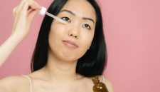 Seorang wanita mengaplikasikan serum anti-aging pada wajahnya, menunjukkan komitmen terhadap perawatan kulit demi mendapatkan tampilan yang sehat dan awet muda. Menggunakan produk yang tepat adalah kunci untuk menjaga elastisitas dan kekenyalan kulit.