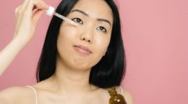 Seorang wanita mengaplikasikan serum anti-aging pada wajahnya, menunjukkan komitmen terhadap perawatan kulit demi mendapatkan tampilan yang sehat dan awet muda. Menggunakan produk yang tepat adalah kunci untuk menjaga elastisitas dan kekenyalan kulit.