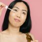 Seorang wanita mengaplikasikan serum anti-aging pada wajahnya, menunjukkan komitmen terhadap perawatan kulit demi mendapatkan tampilan yang sehat dan awet muda. Menggunakan produk yang tepat adalah kunci untuk menjaga elastisitas dan kekenyalan kulit.