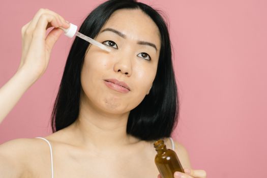 Seorang wanita mengaplikasikan serum anti-aging pada wajahnya, menunjukkan komitmen terhadap perawatan kulit demi mendapatkan tampilan yang sehat dan awet muda. Menggunakan produk yang tepat adalah kunci untuk menjaga elastisitas dan kekenyalan kulit.