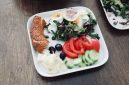 Sebuah piring berisi makanan seimbang dengan beragam warna menunjukkan kombinasi nasi merah, protein ikan panggang, dan sayuran segar, menggambarkan pilihan menu sehat yang menggugah selera.