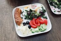 Sebuah piring berisi makanan seimbang dengan beragam warna menunjukkan kombinasi nasi merah, protein ikan panggang, dan sayuran segar, menggambarkan pilihan menu sehat yang menggugah selera.