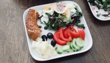 Sebuah piring berisi makanan seimbang dengan beragam warna menunjukkan kombinasi nasi merah, protein ikan panggang, dan sayuran segar, menggambarkan pilihan menu sehat yang menggugah selera.