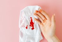 Seorang perempuan sedang mencatat siklus menstruasinya pada kalender, menunjukkan pentingnya memantau kesehatan reproduksi secara berkala. Pemantauan ini membantu memahami pola tubuh dan mengidentifikasi potensi masalah lebih awal.