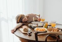Seorang wanita terlihat lelah dan lesu, menggambarkan salah satu gejala utama anemia, yang dapat diatasi dengan asupan makanan bergizi seimbang. Ilustrasi ini menunjukkan pentingnya menjaga nutrisi untuk mendukung energi dan kesehatan optimal.