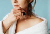 Seorang wanita mengaplikasikan serum vitamin ke wajahnya, menunjukkan momen penting dalam rutinitas perawatan kulit untuk mendapatkan nutrisi optimal. Penggunaan serum secara teratur dapat membantu kulit tampak lebih cerah dan sehat dari waktu ke waktu.