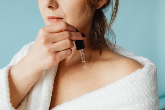 Seorang wanita mengaplikasikan serum vitamin ke wajahnya, menunjukkan momen penting dalam rutinitas perawatan kulit untuk mendapatkan nutrisi optimal. Penggunaan serum secara teratur dapat membantu kulit tampak lebih cerah dan sehat dari waktu ke waktu.