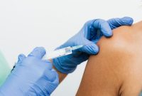 Seorang dokter sedang memberikan vaksinasi HPV kepada seorang remaja, menunjukkan pentingnya program imunisasi untuk melindungi generasi muda dari berbagai penyakit serius. Vaksinasi ini adalah langkah proaktif yang esensial dalam upaya pencegahan kanker dan peningkatan kualitas kesehatan masyarakat.