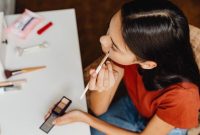 Seorang remaja perempuan dengan kulit cerah sedang mengaplikasikan tabir surya di wajahnya, menunjukkan pentingnya perlindungan kulit dari sinar matahari sebagai bagian dari rutinitas perawatan kulit yang aman. Gambar ini merepresentasikan pendekatan sederhana namun efektif dalam menjaga kesehatan kulit di usia muda.