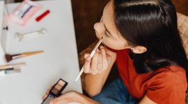 Seorang remaja perempuan dengan kulit cerah sedang mengaplikasikan tabir surya di wajahnya, menunjukkan pentingnya perlindungan kulit dari sinar matahari sebagai bagian dari rutinitas perawatan kulit yang aman. Gambar ini merepresentasikan pendekatan sederhana namun efektif dalam menjaga kesehatan kulit di usia muda.