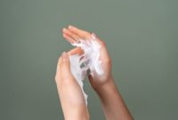 Seorang remaja perempuan sedang mengaplikasikan pembersih wajah lembut, menunjukkan langkah awal dalam rutinitas perawatan kulit yang aman dan efektif untuk mengatasi jerawat tanpa menyebabkan iritasi.